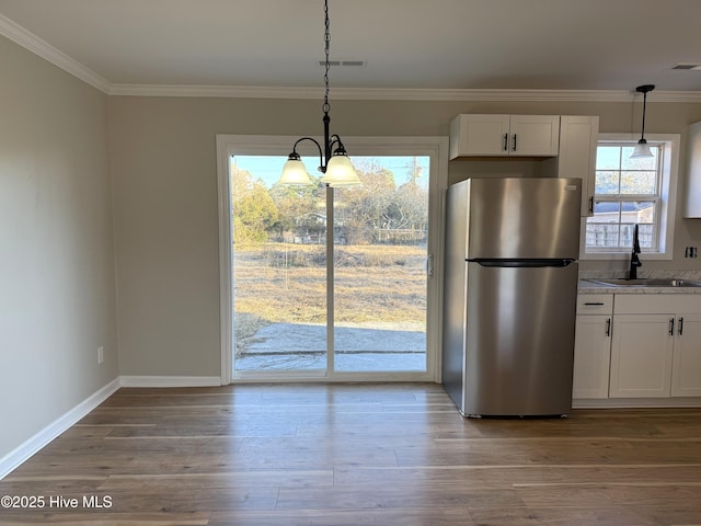 kitchen featuring white cabinets, sink, decorative light fixtures, stainless steel refrigerator, and a chandelier