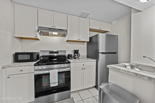 kitchen featuring white cabinets, stainless steel appliances, light tile patterned flooring, and sink