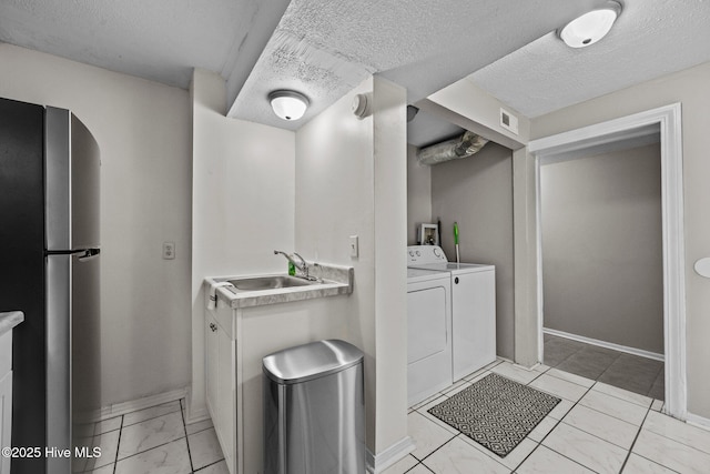 bathroom featuring a textured ceiling, sink, and washing machine and clothes dryer