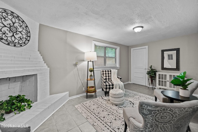 living room with light tile patterned floors, a textured ceiling, and a brick fireplace