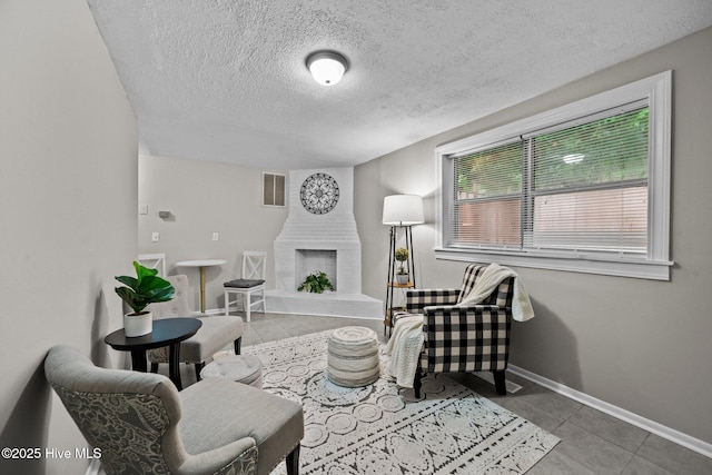 tiled living room featuring a large fireplace and a textured ceiling