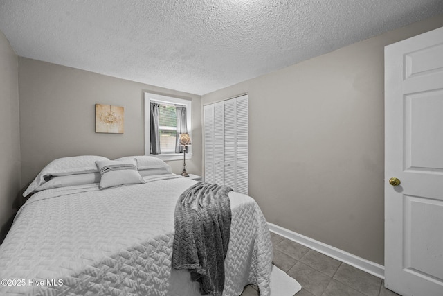 bedroom with a closet, dark tile patterned floors, and a textured ceiling