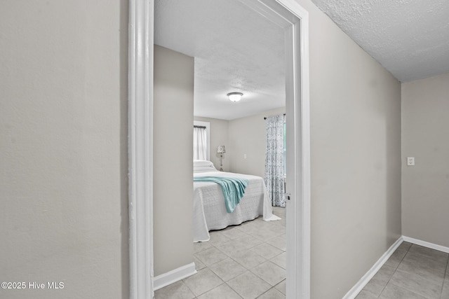 corridor featuring light tile patterned flooring and a textured ceiling