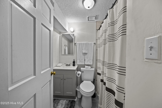 bathroom with vanity, toilet, a textured ceiling, and walk in shower