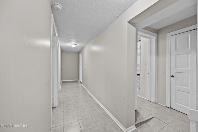 hall with light tile patterned floors and a textured ceiling