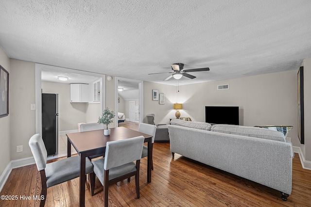 living room featuring a textured ceiling, dark hardwood / wood-style flooring, and ceiling fan