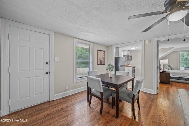 dining area with a textured ceiling, dark hardwood / wood-style flooring, and a healthy amount of sunlight