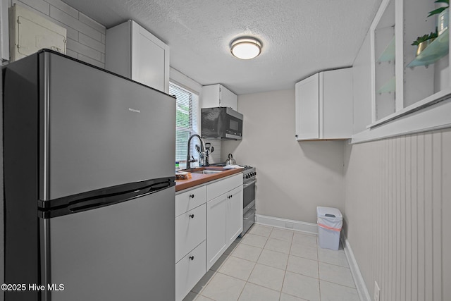 kitchen with white cabinetry, sink, a textured ceiling, light tile patterned flooring, and appliances with stainless steel finishes