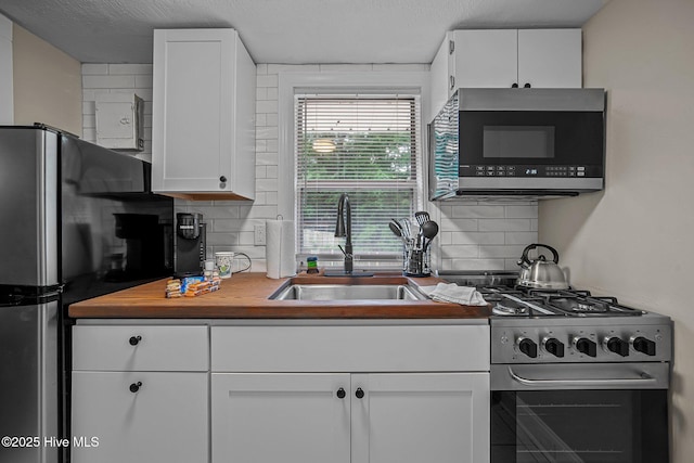 kitchen with decorative backsplash, a textured ceiling, stainless steel appliances, sink, and white cabinets