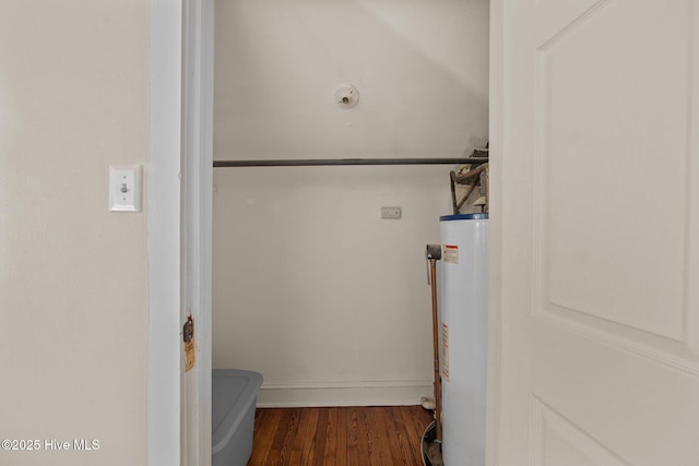 clothes washing area with gas water heater and dark wood-type flooring