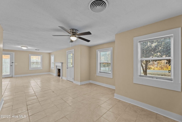 unfurnished living room with ceiling fan, light tile patterned flooring, and a textured ceiling