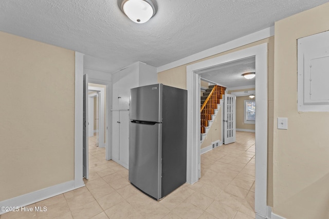 kitchen featuring stainless steel fridge, a textured ceiling, and electric panel