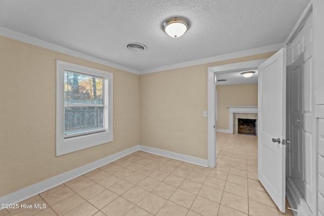 tiled spare room with ornamental molding, a textured ceiling, and a tile fireplace