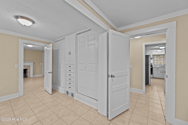 hallway with sink, light tile patterned floors, and a textured ceiling