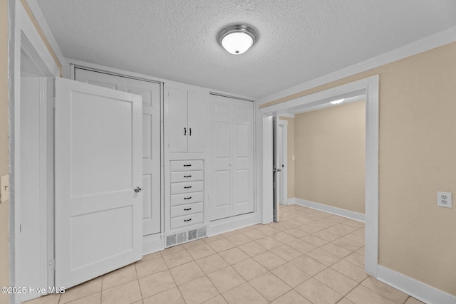 interior space featuring a closet, light tile patterned floors, and a textured ceiling