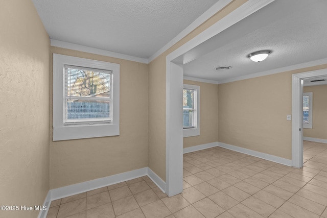 tiled empty room with crown molding and a textured ceiling