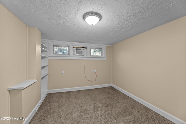 basement with carpet, a textured ceiling, and a wall mounted air conditioner