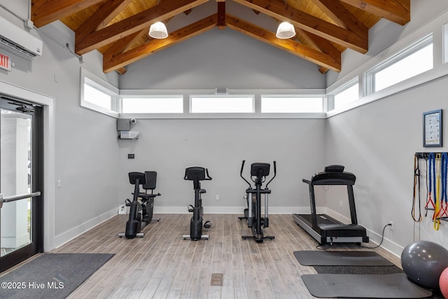 workout room with light hardwood / wood-style flooring, a wall mounted air conditioner, plenty of natural light, and high vaulted ceiling