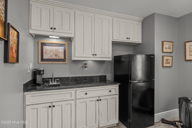 kitchen with black fridge, sink, and white cabinets