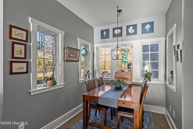 dining area featuring a wealth of natural light, dark parquet floors, and an inviting chandelier