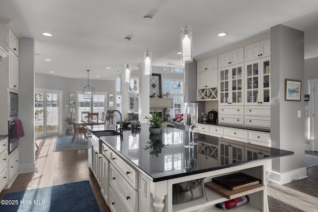 kitchen with a large island with sink, stainless steel appliances, hanging light fixtures, and sink