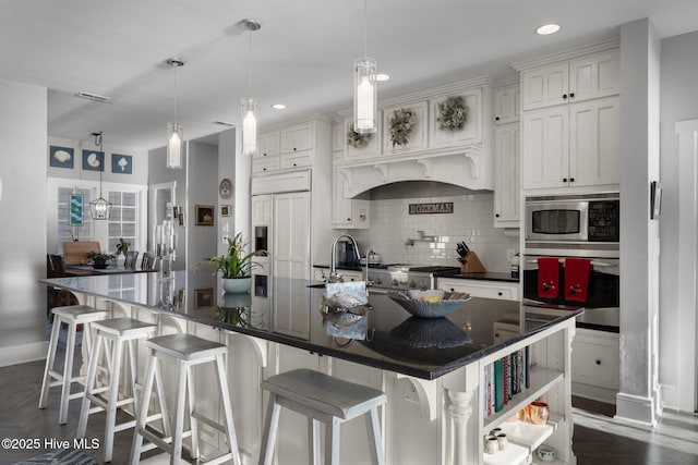 kitchen featuring built in appliances, decorative light fixtures, a spacious island, and tasteful backsplash