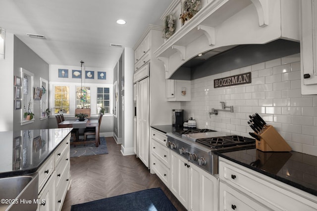 kitchen featuring stainless steel gas stovetop, white cabinets, dark parquet floors, decorative backsplash, and decorative light fixtures