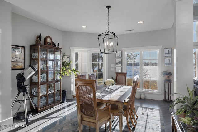 dining area with dark parquet flooring and an inviting chandelier