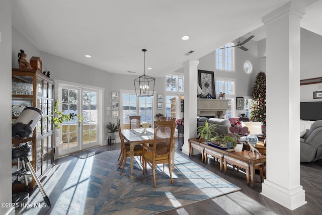 dining area with decorative columns, dark parquet floors, and ceiling fan with notable chandelier