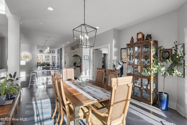 dining room featuring decorative columns, dark parquet floors, and a chandelier