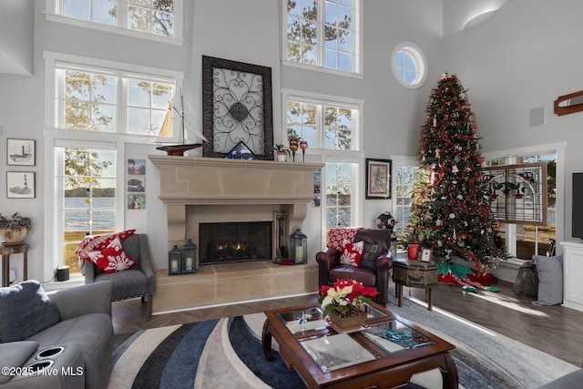 living room with a fireplace, a towering ceiling, and parquet floors