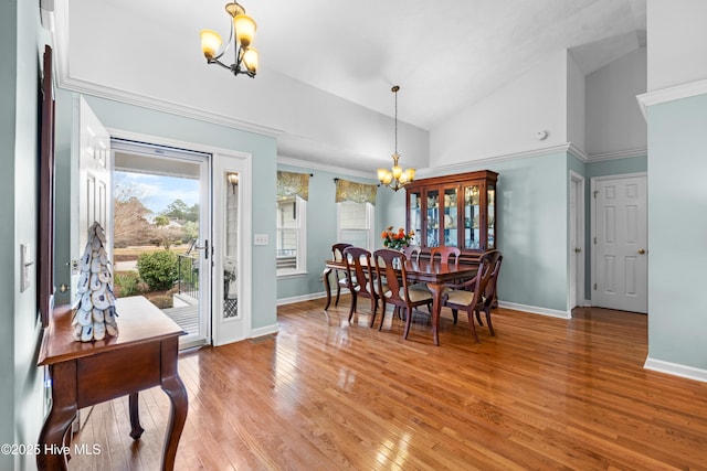 dining area with light wood-type flooring, an inviting chandelier, and high vaulted ceiling