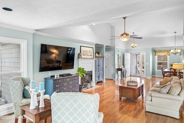 living room with ceiling fan with notable chandelier, light hardwood / wood-style flooring, and lofted ceiling