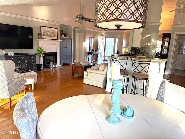 dining space featuring wood-type flooring, sink, vaulted ceiling, ceiling fan, and crown molding