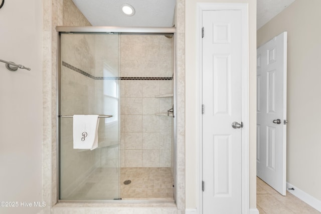 bathroom featuring an enclosed shower, tile patterned floors, and a textured ceiling