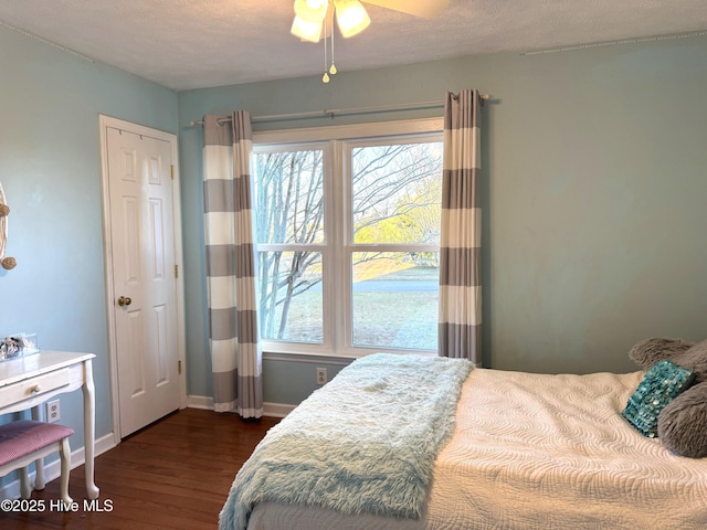 bedroom with dark wood-type flooring, ceiling fan, and a textured ceiling