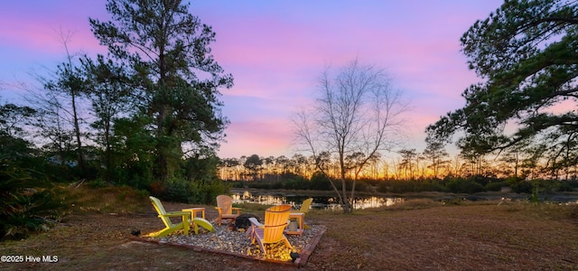 yard at dusk with a water view and an outdoor fire pit