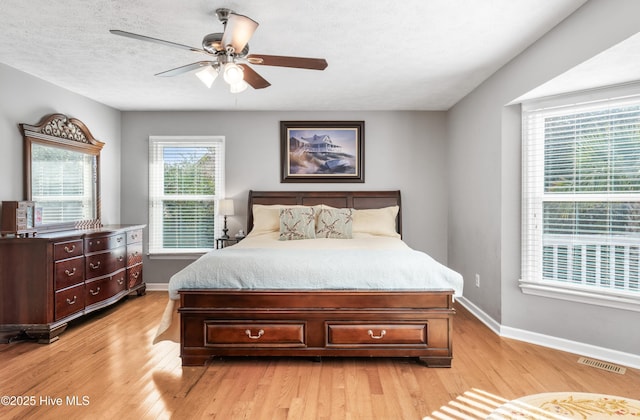 bedroom with ceiling fan, multiple windows, and light wood-type flooring