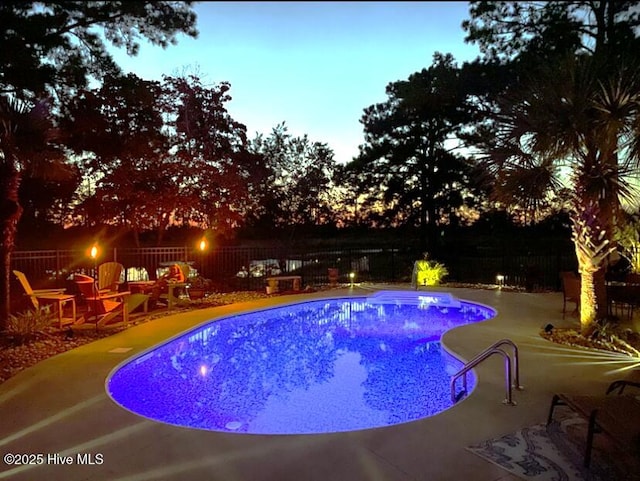 pool at dusk with a patio area