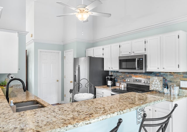 kitchen featuring white cabinets, kitchen peninsula, appliances with stainless steel finishes, and sink