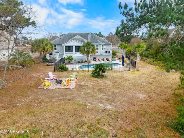 back of property featuring a fenced in pool and a fire pit