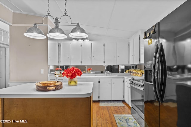 kitchen with pendant lighting, light wood-type flooring, a kitchen island, white cabinetry, and stainless steel appliances