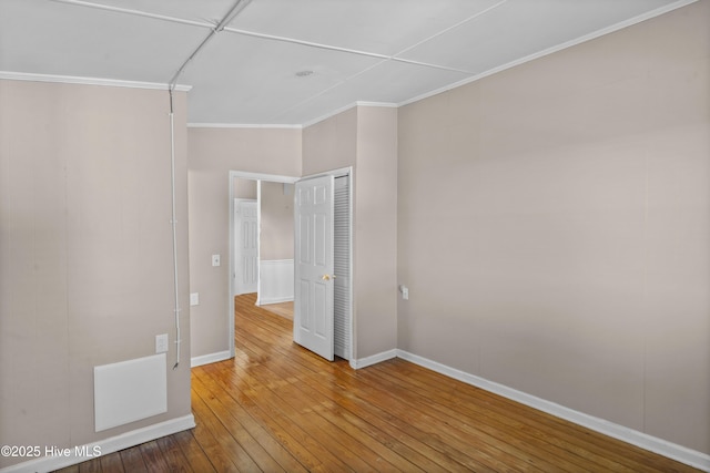 empty room with wood-type flooring and crown molding