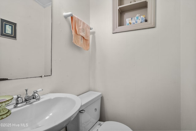 bathroom featuring toilet, ornamental molding, and sink