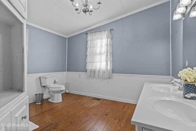 bathroom with a chandelier, wood-type flooring, vaulted ceiling, toilet, and vanity