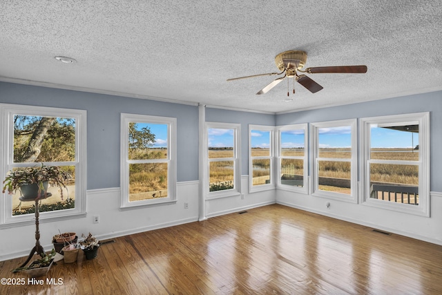 unfurnished sunroom featuring ceiling fan and a healthy amount of sunlight