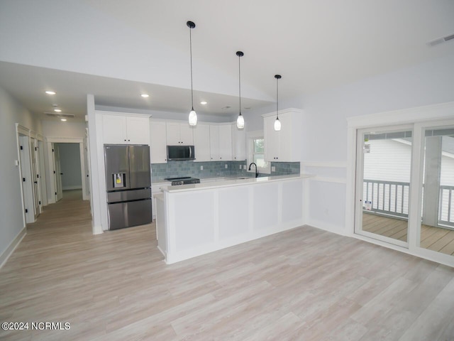 kitchen featuring a healthy amount of sunlight, hanging light fixtures, stainless steel appliances, kitchen peninsula, and white cabinets