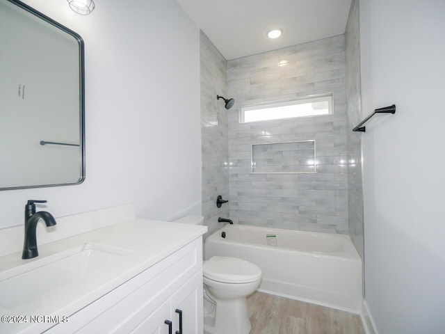 full bathroom with vanity, tiled shower / bath combo, hardwood / wood-style flooring, and toilet