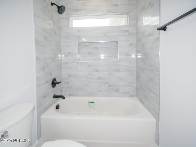 bathroom featuring toilet and tiled shower / bath