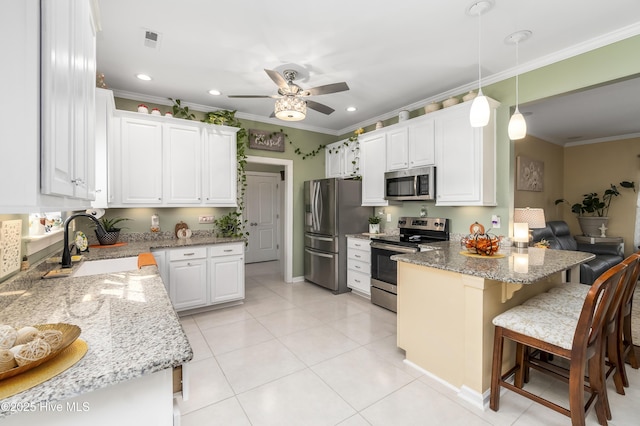 kitchen featuring white cabinetry, hanging light fixtures, stainless steel appliances, light stone counters, and a breakfast bar area